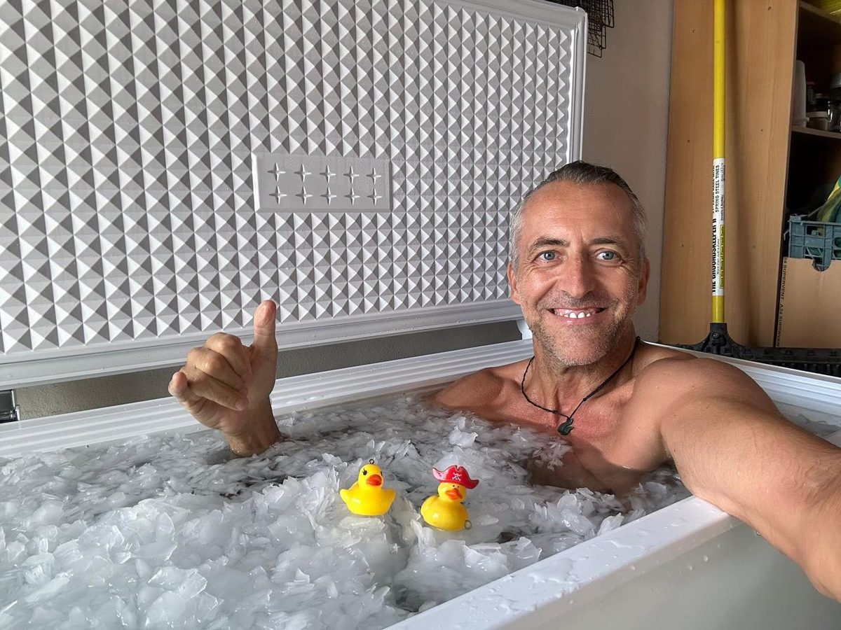 Thomas smiling in his ice bath with two rubber ducks